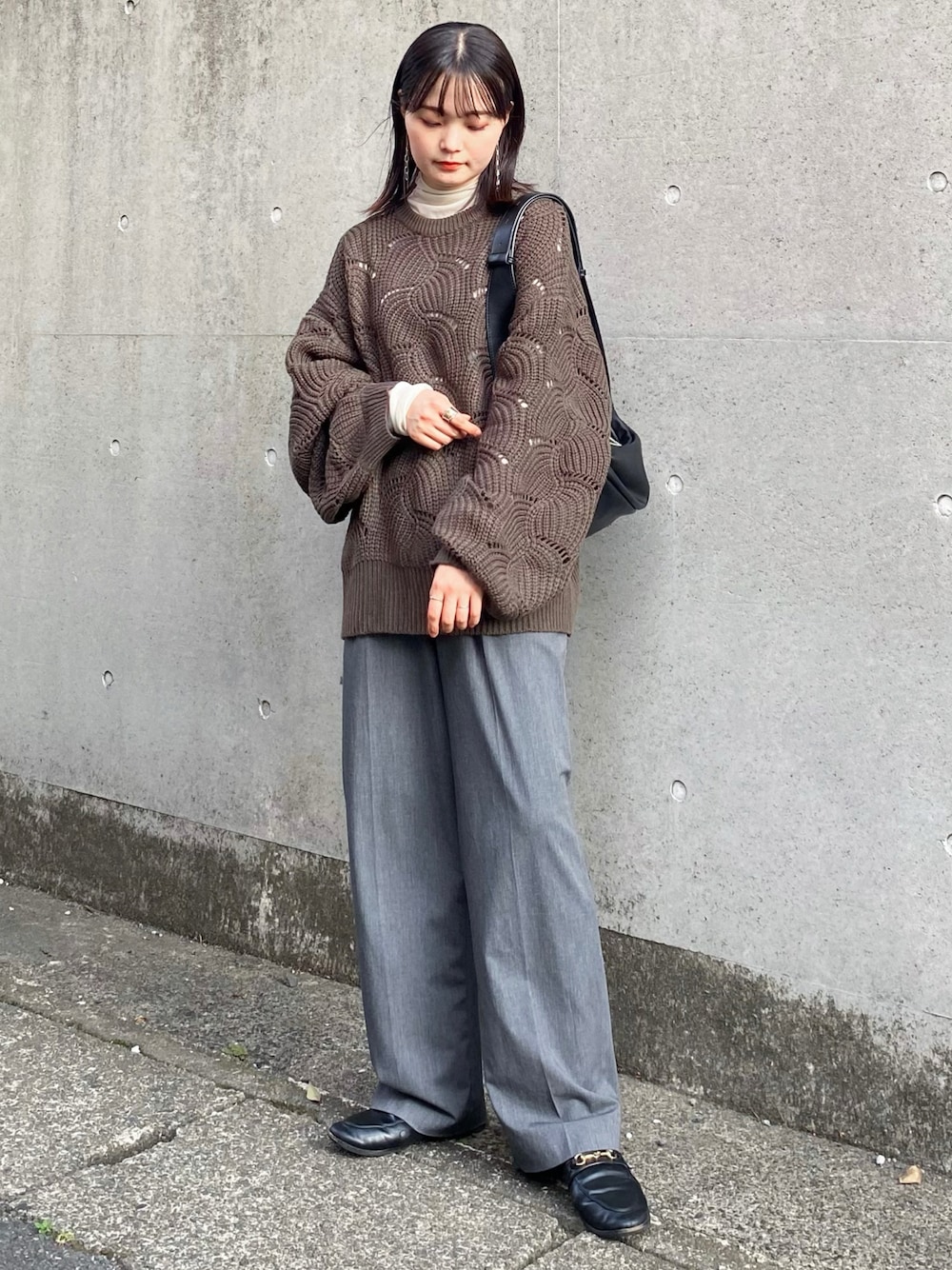 グリーン系のニット/セーター、グレー系のスラックス、ブラック系のショルダーバッグを着用したレディースの秋コーディネートの1枚目の写真