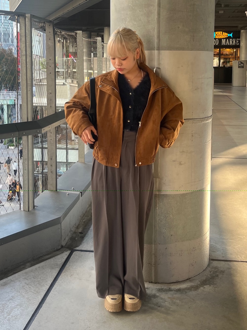 グレー系のスラックス、ブラウン系のブルゾン、ブルー系のニット/セーターを着用したレディースの秋コーディネートの1枚目の写真