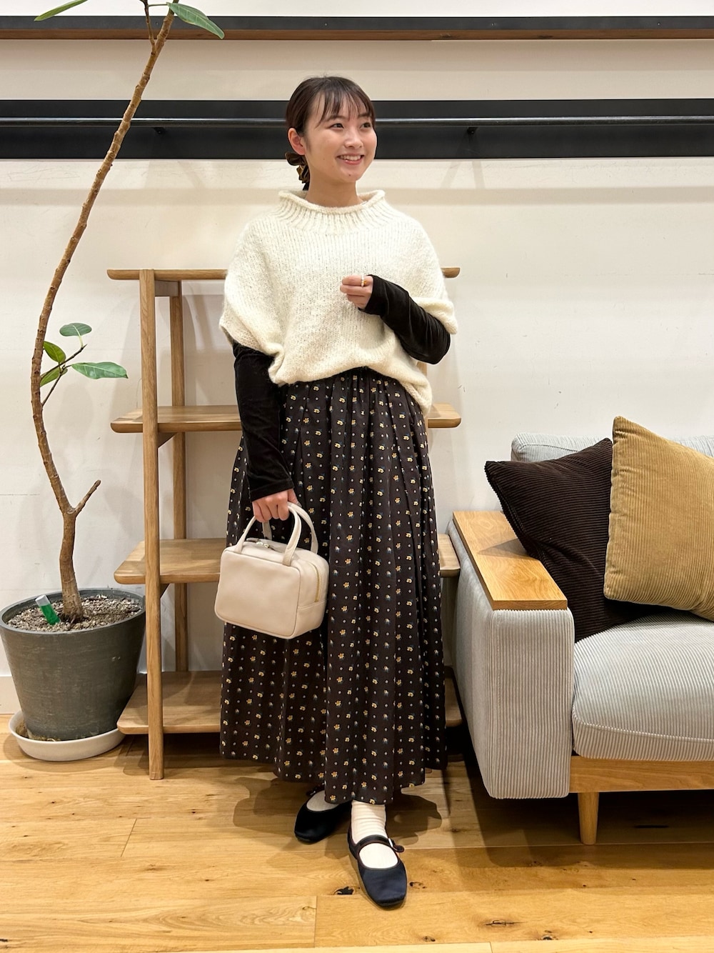 ホワイト系のニット/セーター、ブラウン系のTシャツ/カットソー、グレー系のボストンバッグを着用したレディースの秋コーディネートの1枚目の写真