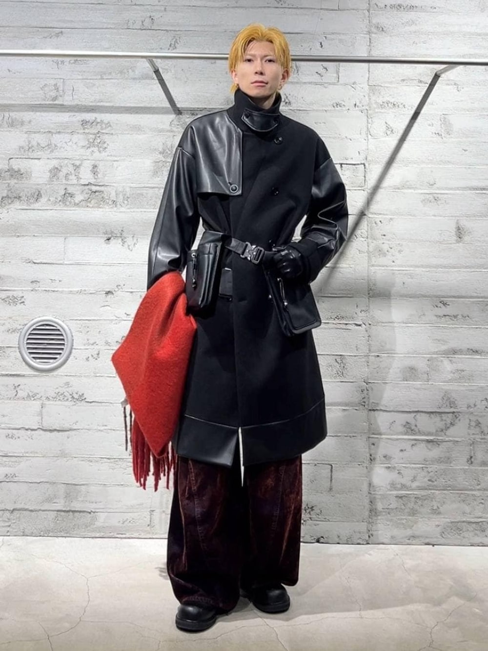 ブラック系のトレンチコート、ブラック系のドレスシューズ、レッド系のデニムパンツを着用したメンズの秋コーディネートの1枚目の写真