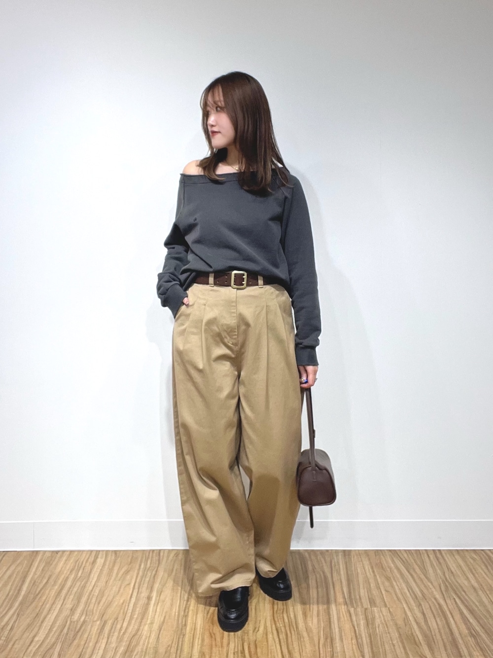 グレー系のスウェット、ベージュ系のチノパンツ、ブラウン系のショルダーバッグを着用したレディースの冬コーディネートの1枚目の写真