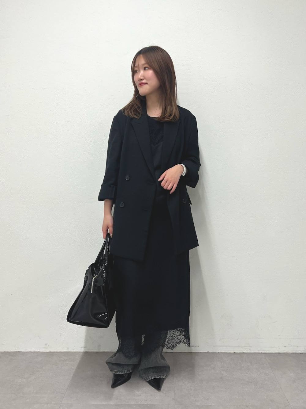 ブラック系のテーラードジャケット、ブラック系のキャミソール、グレー系のデニムパンツを着用したレディースの冬コーディネートの1枚目の写真