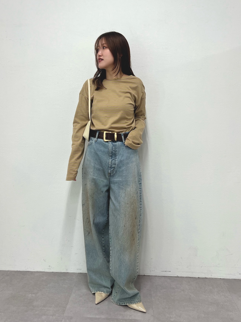 ベージュ系のTシャツ/カットソー、ブルー系のデニムパンツ、ホワイト系のショルダーバッグを着用したレディースの冬コーディネートの1枚目の写真