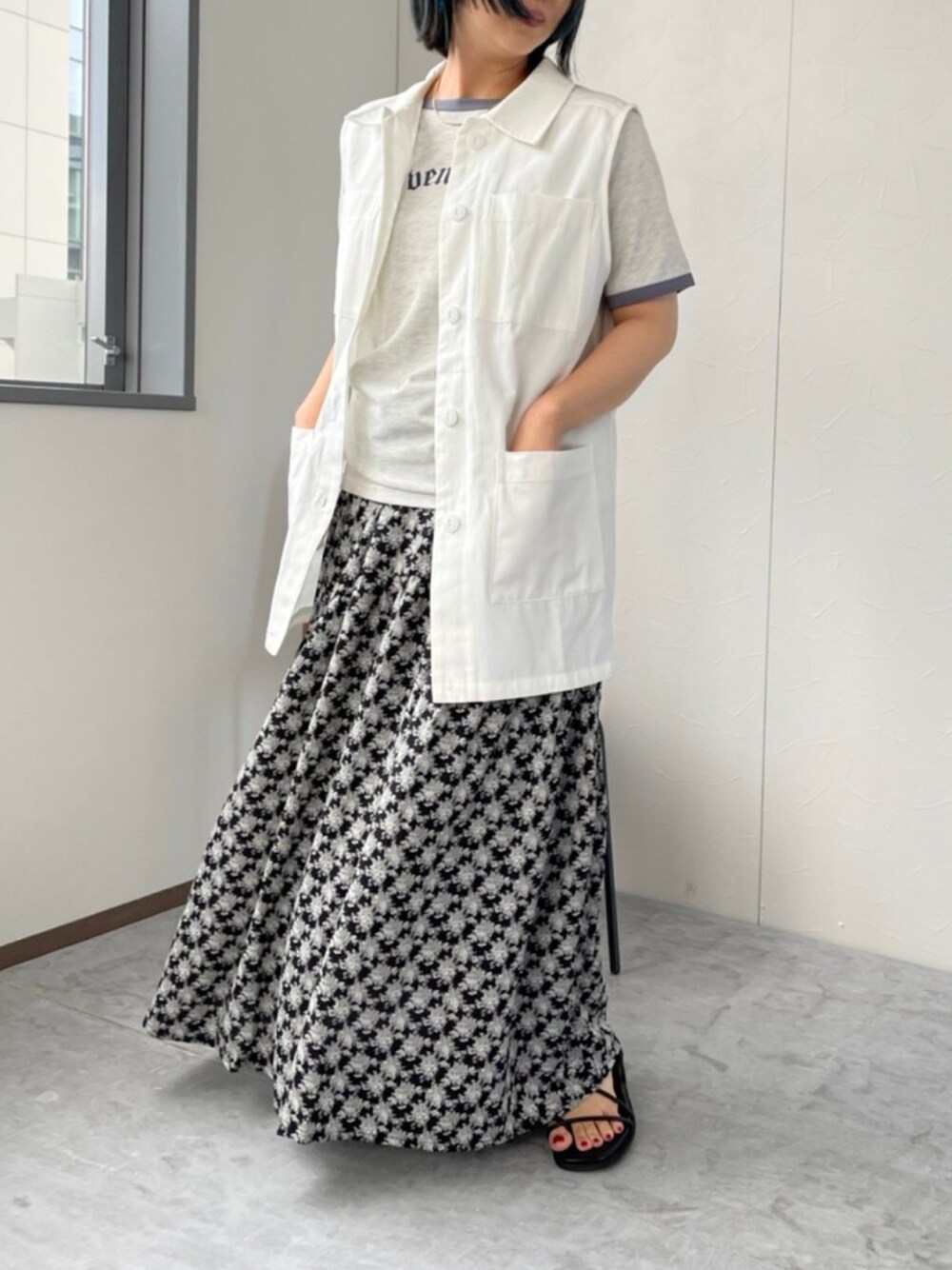 ブラック系のスカート、ホワイト系のベスト、ベージュ系のTシャツ/カットソーを着用したレディースの夏コーディネートの1枚目の写真