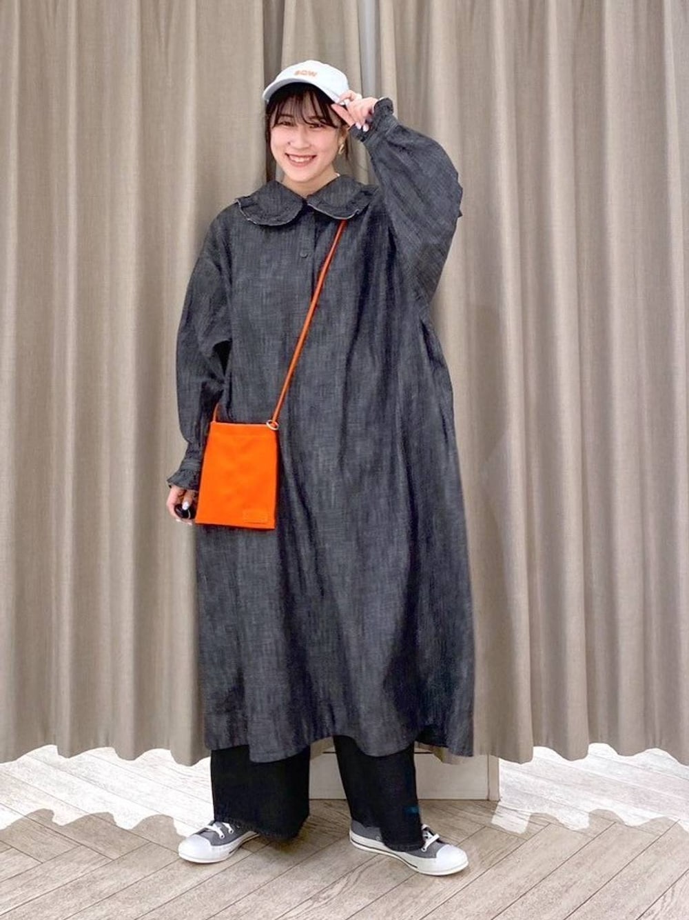 ブラック系のデニムパンツ、グレー系のスニーカー、オレンジ系のショルダーバッグを着用したレディースの秋コーディネートの1枚目の写真