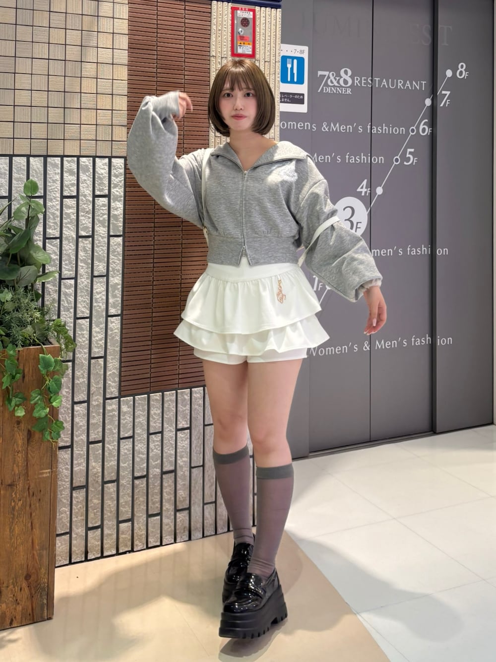 グレー系のパーカー、ホワイト系のスカート、ホワイト系のバックパック/リュックを着用したレディースの春コーディネートの1枚目の写真