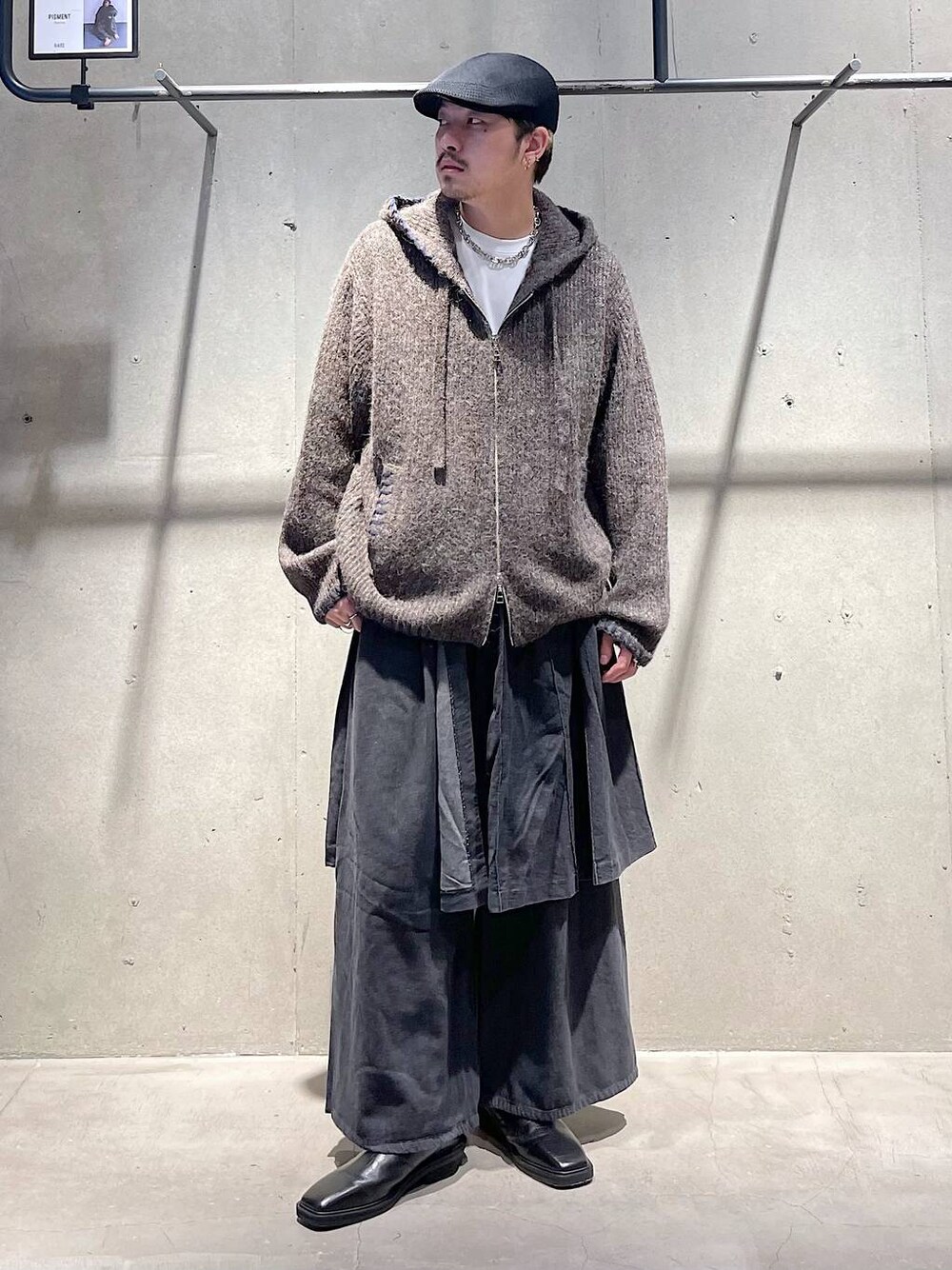 グレー系のスラックス、ブラック系のブーツ、ブラウン系のニット/セーターを着用したメンズの冬コーディネートの1枚目の写真