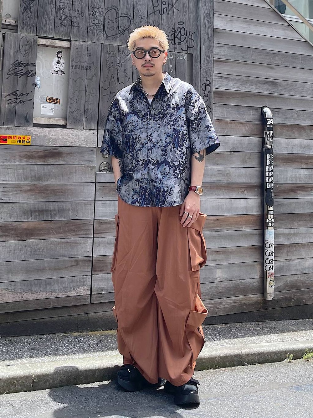 ブラック系のサンダル、オレンジ系のカーゴパンツ、ホワイト系のタンクトップを着用したメンズの夏コーディネートの1枚目の写真