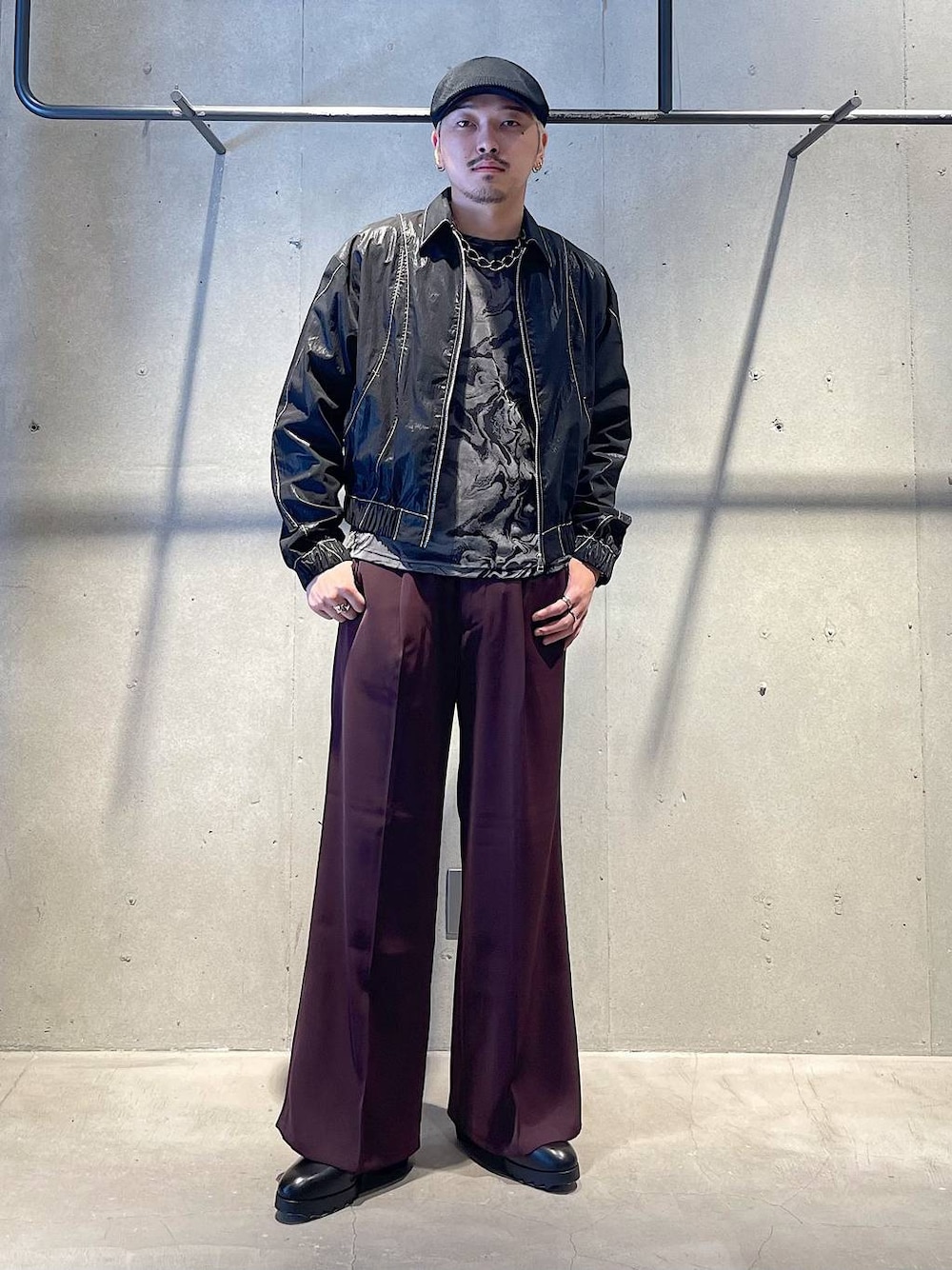 レッド系のスラックス、ブラック系のドレスシューズ、ブラック系のブルゾンを着用したメンズの秋コーディネートの1枚目の写真