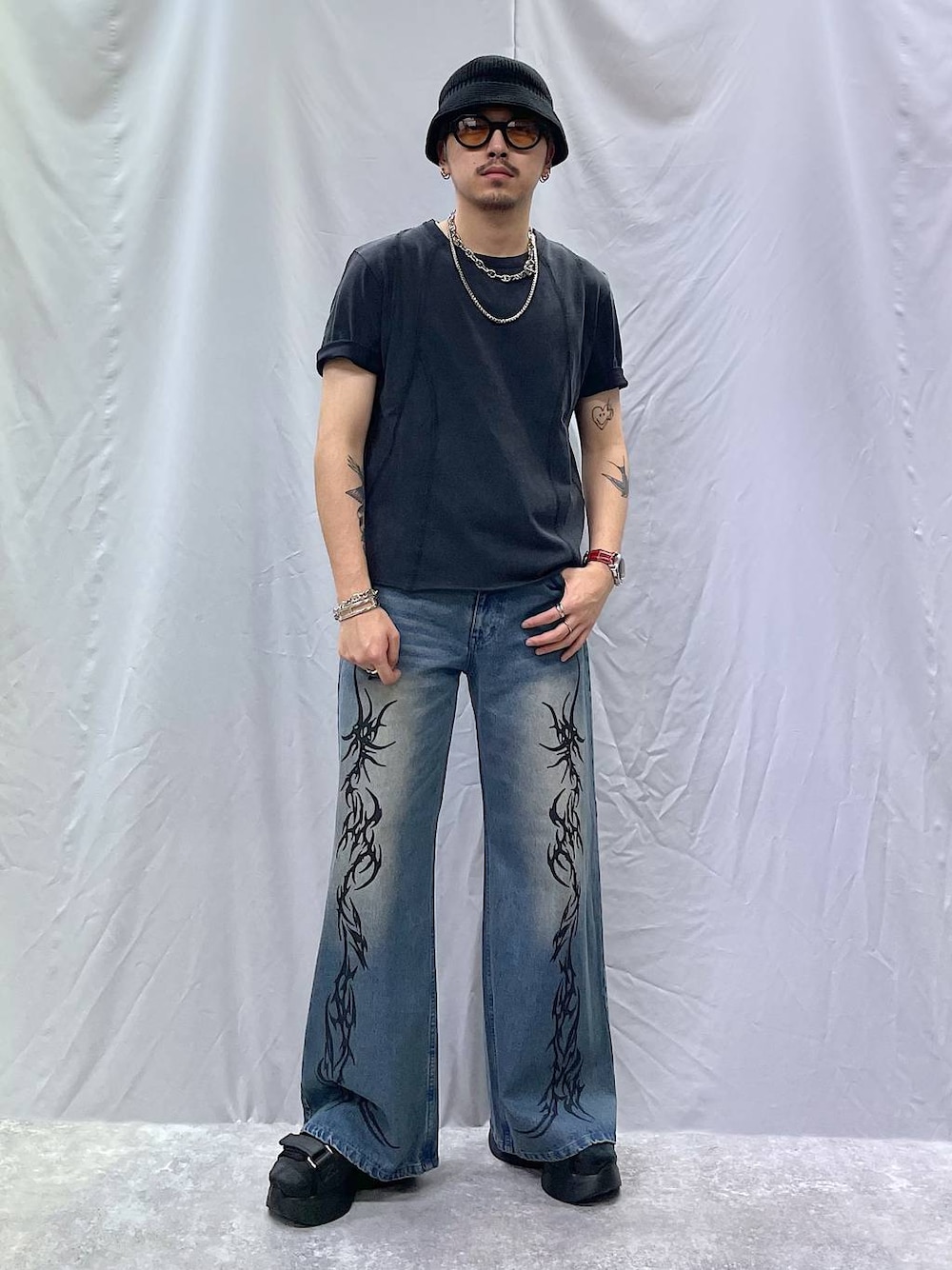 ブラック系のサンダル、ブラック系のTシャツ/カットソー、ブルー系のデニムパンツを着用したメンズの夏コーディネートの1枚目の写真