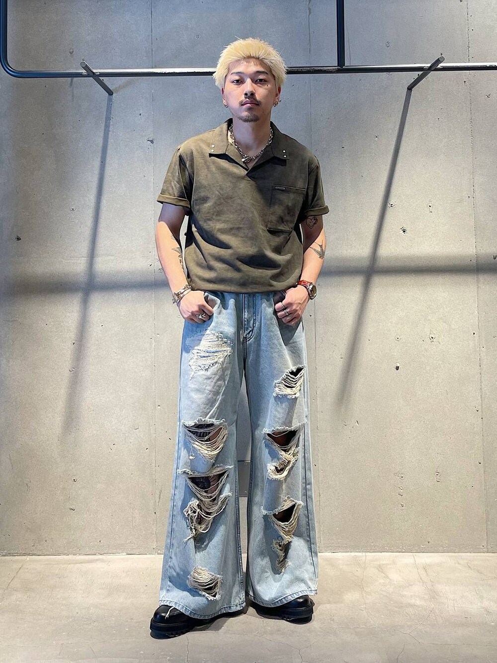 ブルー系のデニムパンツ、ブラック系のドレスシューズ、グリーン系のTシャツ/カットソーを着用したメンズの秋コーディネートの1枚目の写真