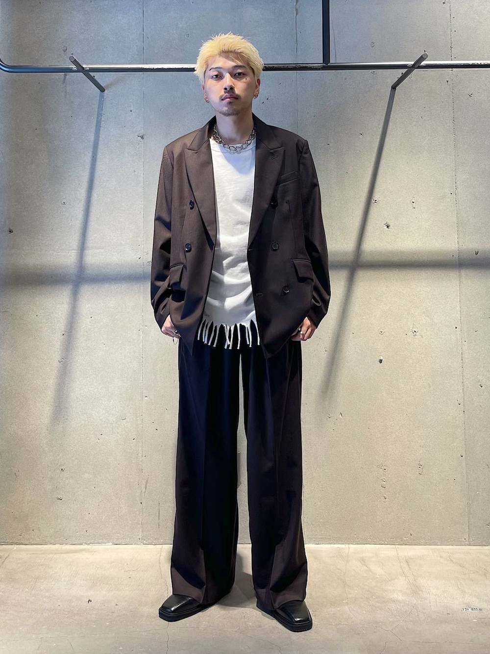 ブラック系のテーラードジャケット、ブラック系のスラックス、ブラック系のブーツを着用したメンズの秋コーディネートの1枚目の写真