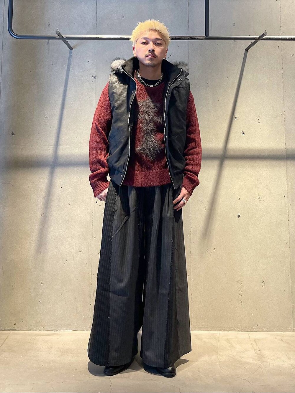 ブラック系のその他パンツ、ブラック系のドレスシューズ、レッド系のニット/セーターを着用したメンズの冬コーディネートの1枚目の写真