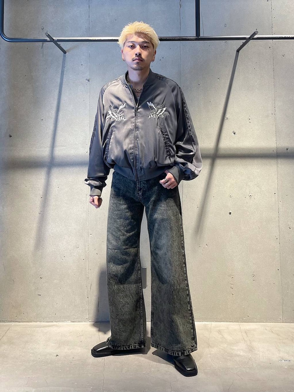 グリーン系のデニムパンツ、グレー系のスカジャン、ブラック系のブーツを着用したメンズの秋コーディネートの1枚目の写真