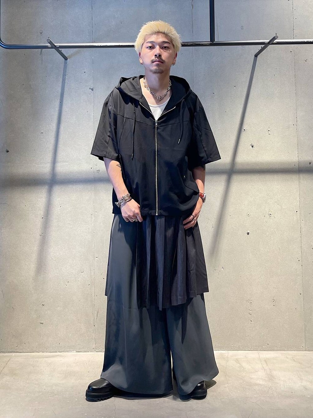 グレー系のスラックス、ブラック系のドレスシューズ、ホワイト系のタンクトップを着用したメンズの秋コーディネートの1枚目の写真