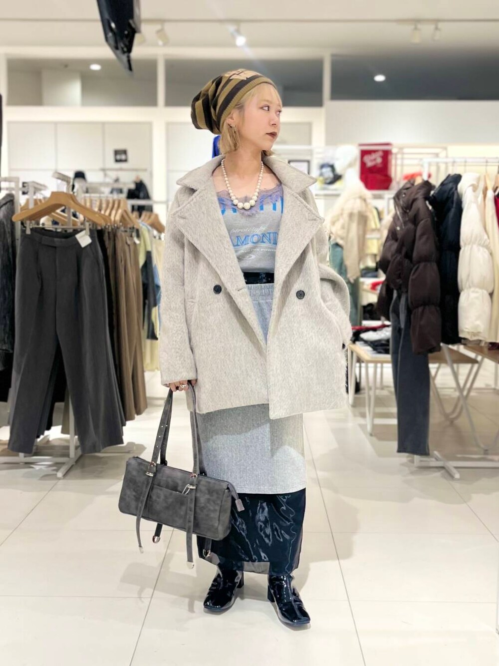 ブラック系のブーツ、ブラック系のスカート、グレー系のボストンバッグを着用したレディースの秋コーディネートの1枚目の写真