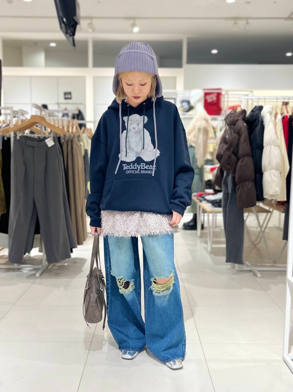 シルバー系のブーツ、ブルー系のデニムパンツ、ブラウン系のボストンバッグを着用したレディースの冬コーディネートの1枚目の写真