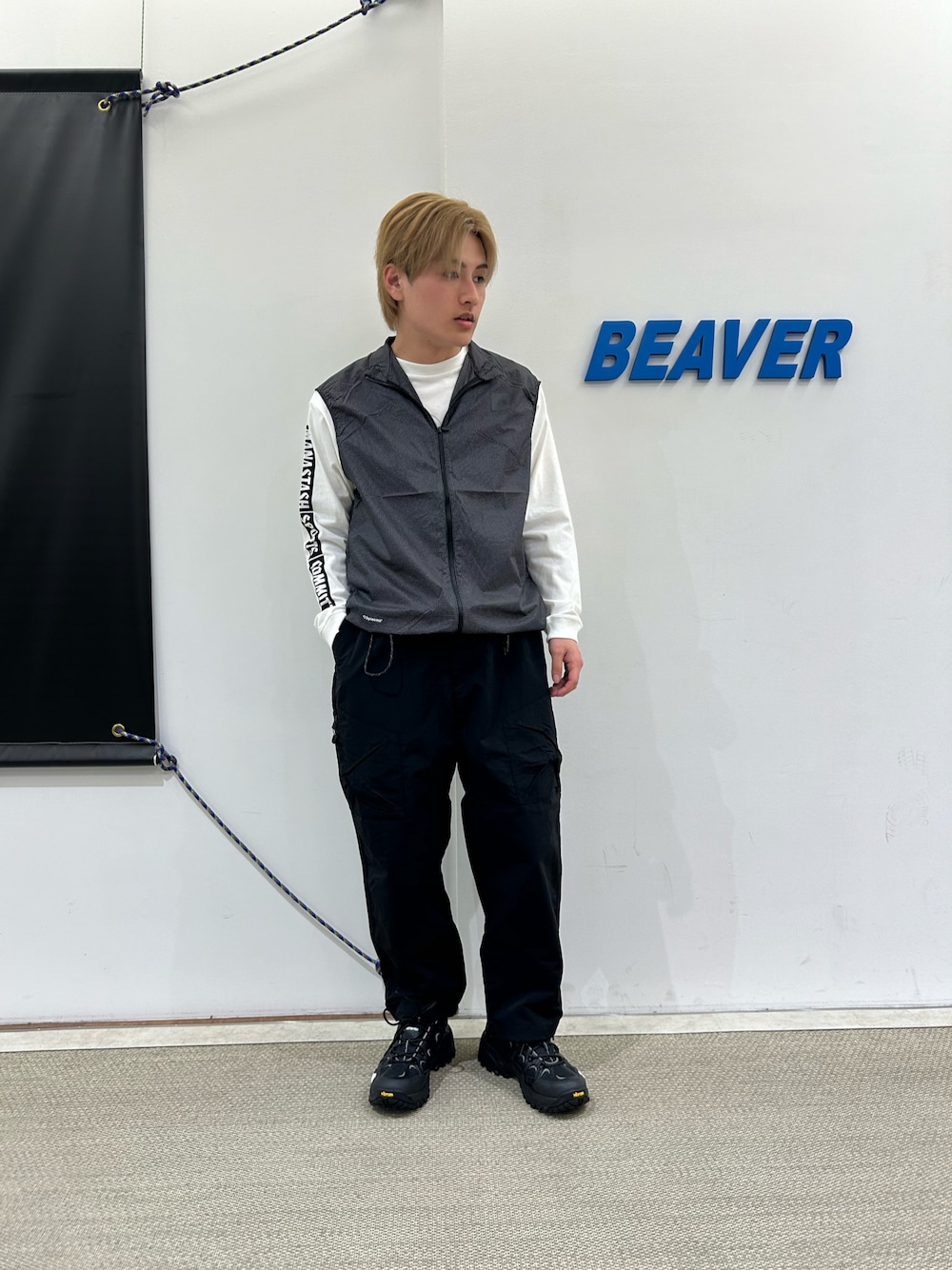 「春コーデ、春、春服、ブラックコーデ、ブラック、ノースフェイス、THE NORTH FACE、ベスト、ロンT、Tシャツ、マナスタッシュ、MANASTASH、CMF Outdoor Garment、スニーカー、雨の日コーデ」｜「MANASTASHのMANASTASH/マナスタッシュ　CiTee L/S TEE SSD/SPORTS STORE DAY/シティ ロンT スポーツストア デイ（Tシャツ/カットソー、ホワイト系）」を使った、拓海さん（メンズ・168cm）の春コーディネートの1枚目の写真