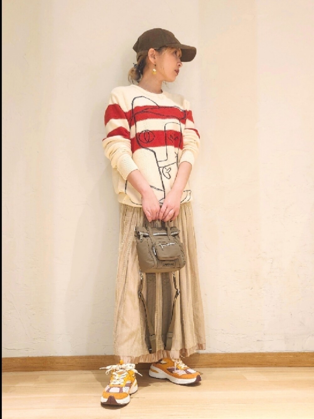 ホワイト系のニット/セーター、その他のスニーカー、グリーン系のボディバッグ/ウエストポーチを着用したレディースの春コーディネートの1枚目の写真