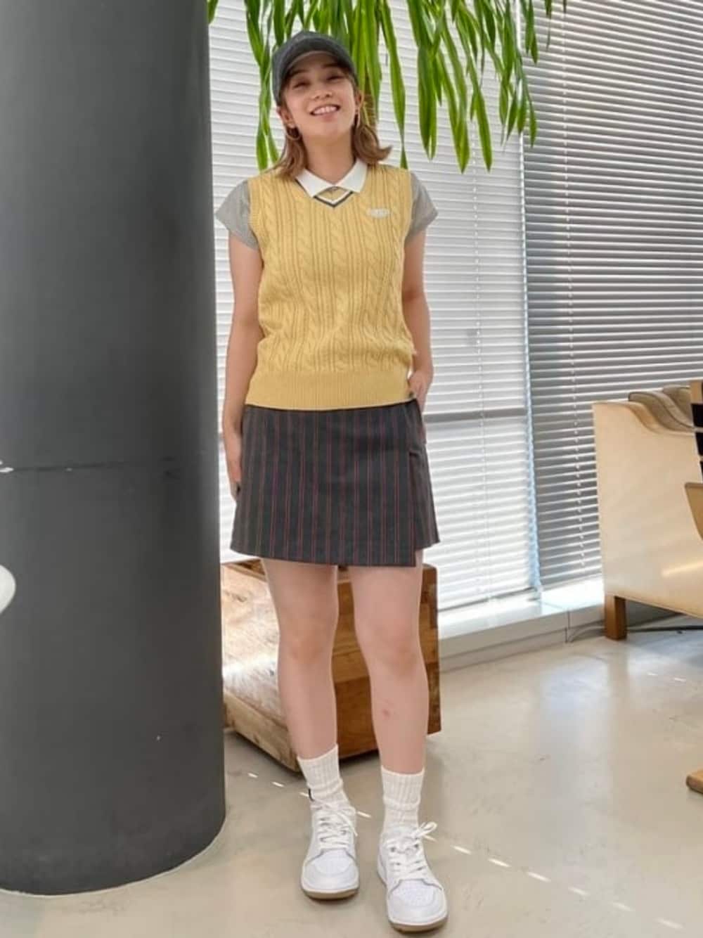 イエロー系のニット/セーター、ブルー系のポロシャツを着用したレディースの夏コーディネートの1枚目の写真