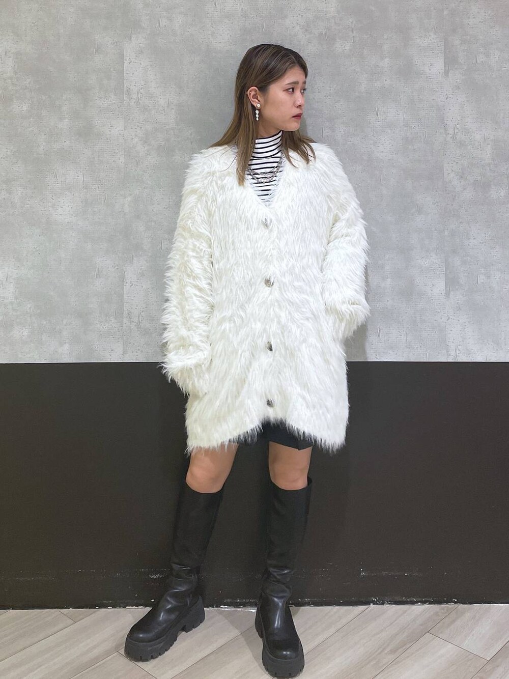 ホワイト系のカーディガン/ボレロ、ブラック系のブーツ、ブラック系のスカートを着用したレディースの秋コーディネートの1枚目の写真