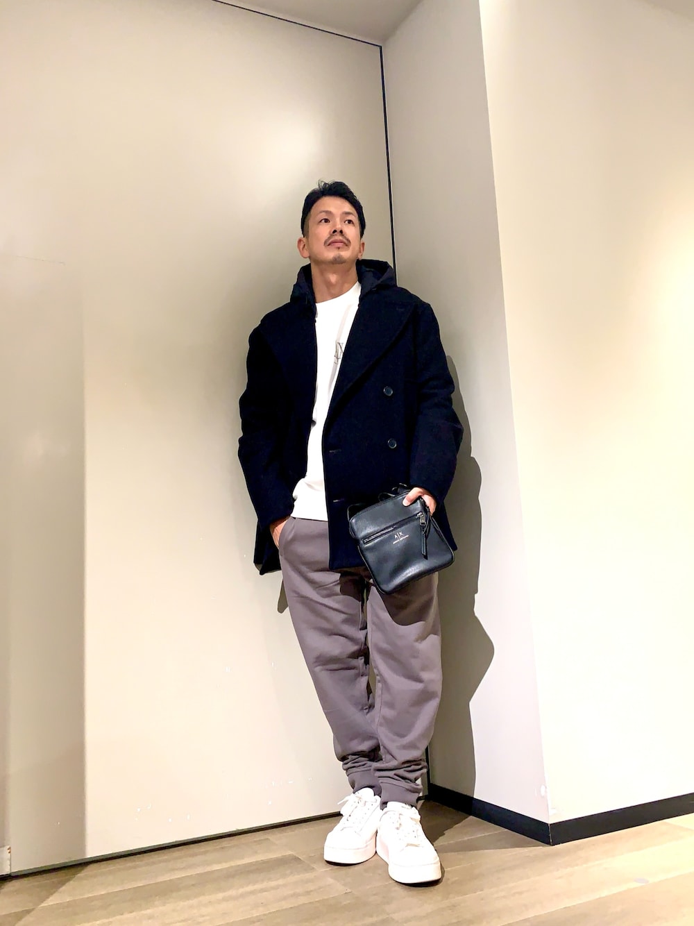 ホワイト系のスニーカー、グレー系のスウェットパンツ、ブラック系のショルダーバッグを着用したメンズの秋コーディネートの1枚目の写真
