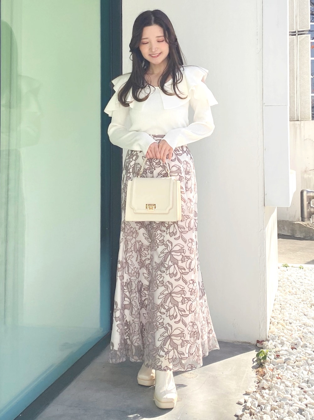 ホワイト系のブーツ、ホワイト系のニット/セーター、ホワイト系のハンドバッグを着用したレディースの冬コーディネートの1枚目の写真