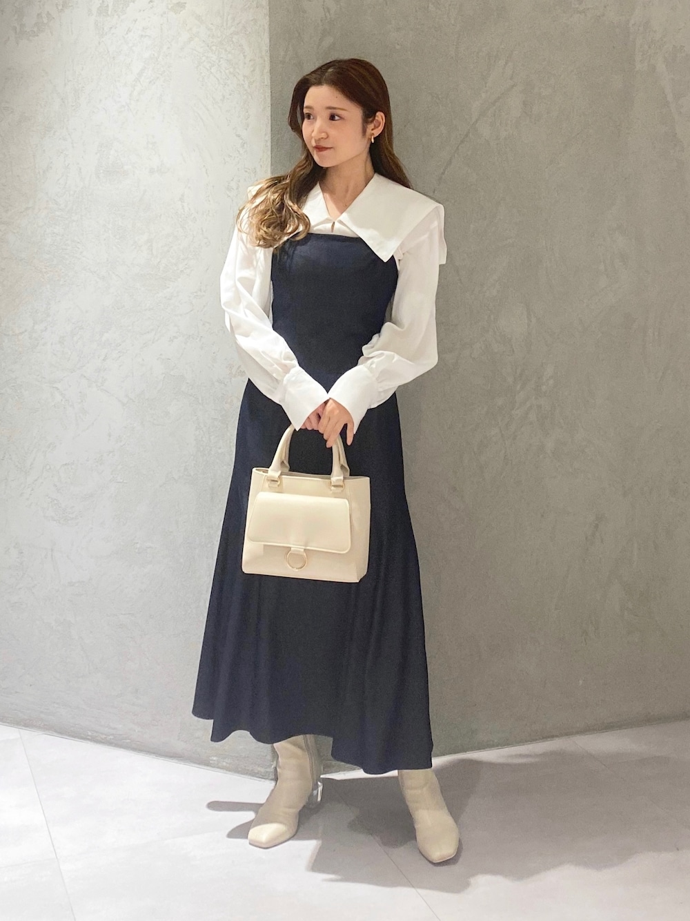 ホワイト系のブーツ、ブルー系のワンピース、ホワイト系のハンドバッグを着用したレディースの冬コーディネートの1枚目の写真