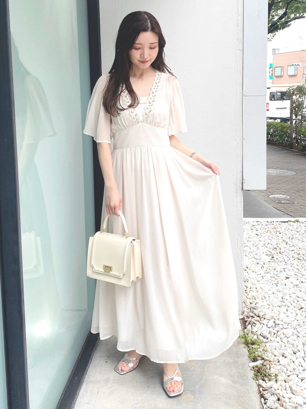 ホワイト系のハンドバッグ、ホワイト系のワンピース、シルバー系のサンダルを着用したレディースの夏コーディネートの1枚目の写真