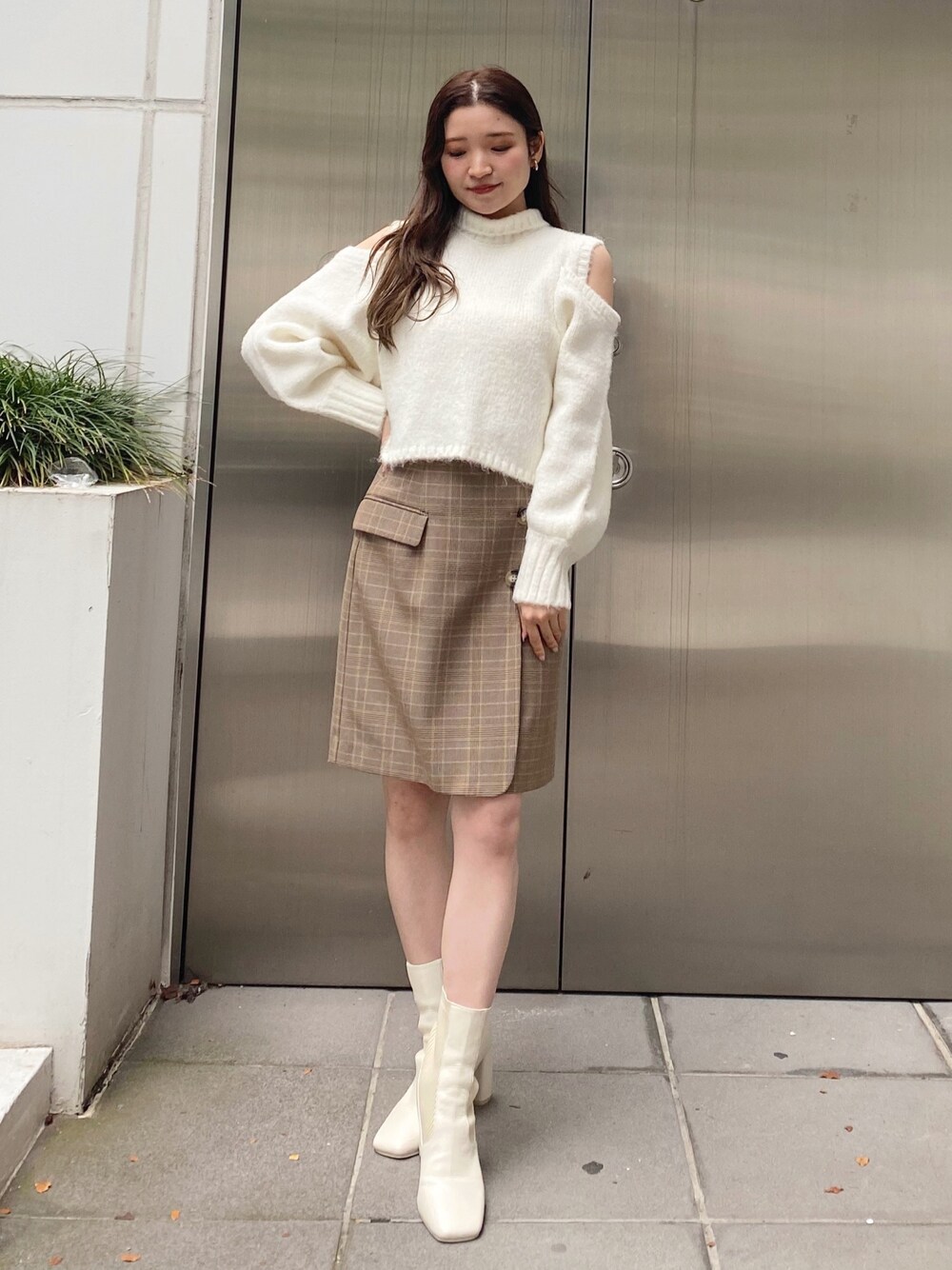 ホワイト系のニット/セーター、ベージュ系のスカート、ホワイト系のブーツを着用したレディースの秋コーディネートの1枚目の写真