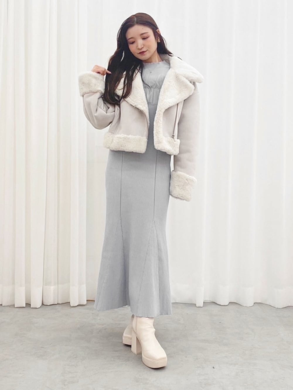 ブルー系のワンピース、ホワイト系のブーツ、グレー系のムートンコートを着用したレディースの秋コーディネートの1枚目の写真