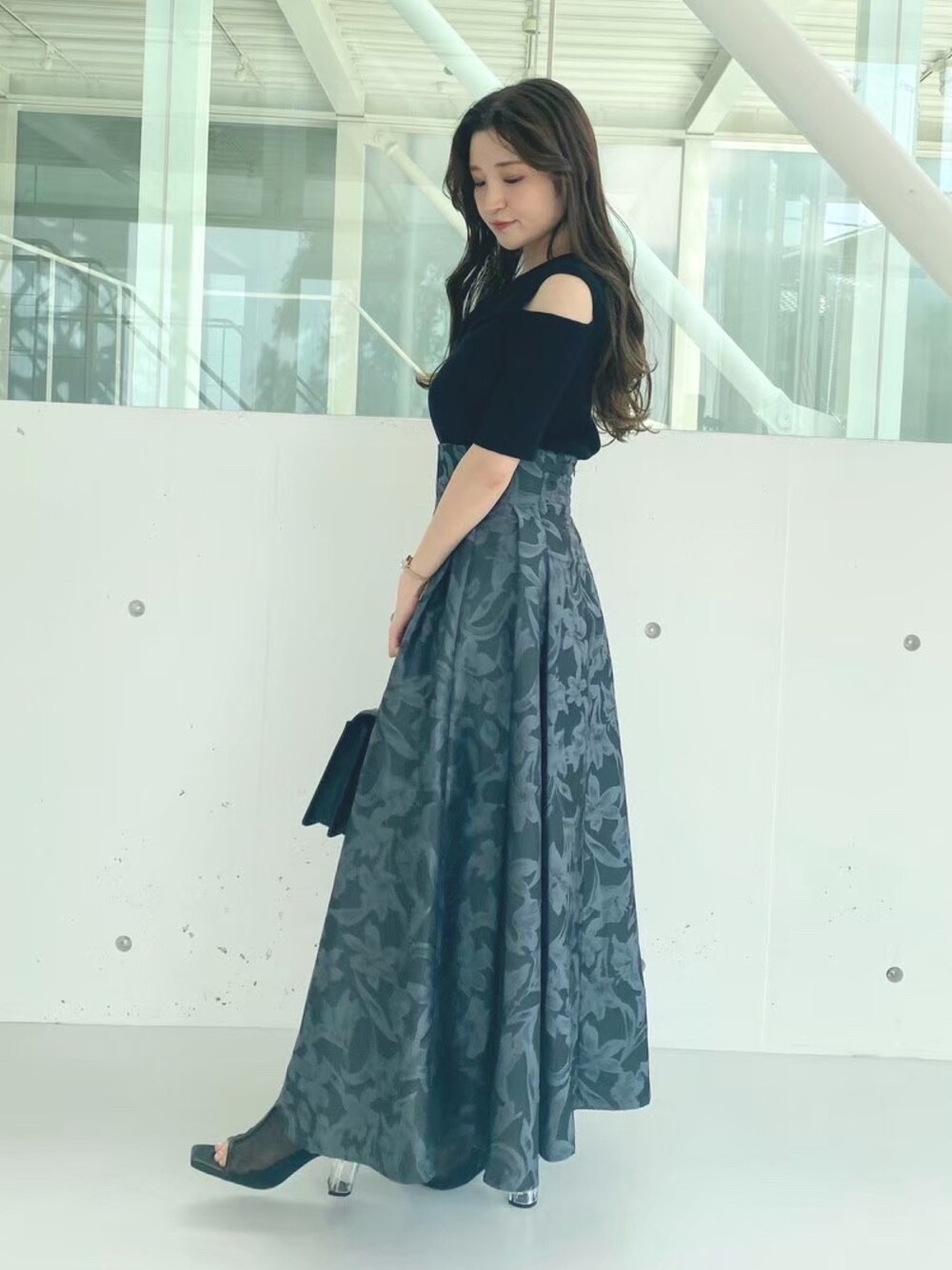 ブラック系のハンドバッグ、ブラック系のブーツ、ブラック系のニット/セーターを着用したレディースの秋コーディネートの1枚目の写真