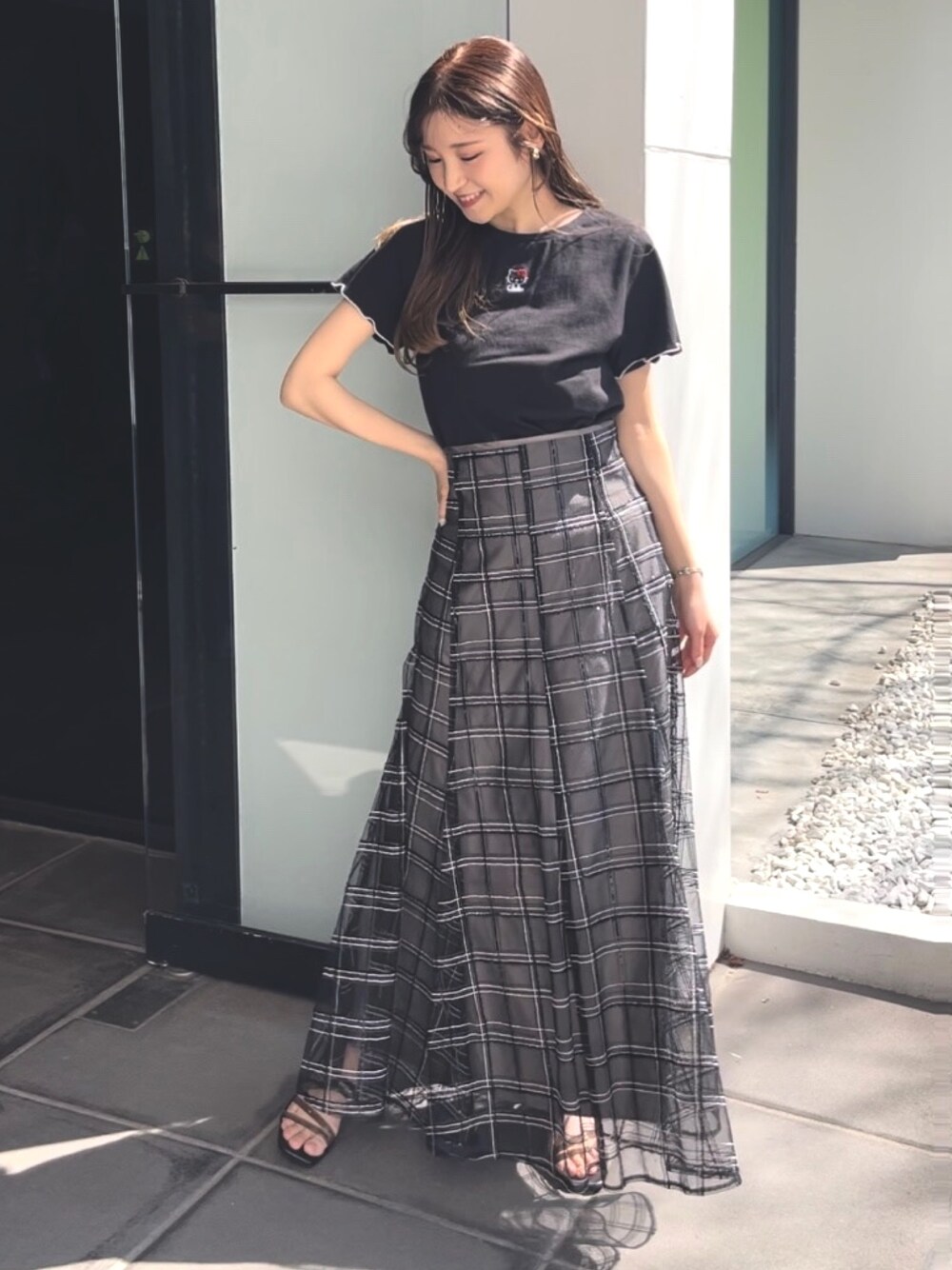 ブラック系のサンダル、ブラック系のスカート、ブラック系のTシャツ/カットソーを着用したレディースの春コーディネートの1枚目の写真