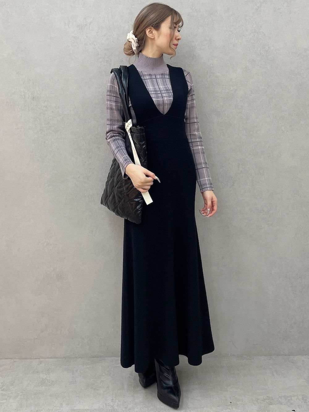 パープル系のニット/セーター、ブラック系のブーツ、ブラック系のジャンパースカートを着用したレディースの秋コーディネートの1枚目の写真