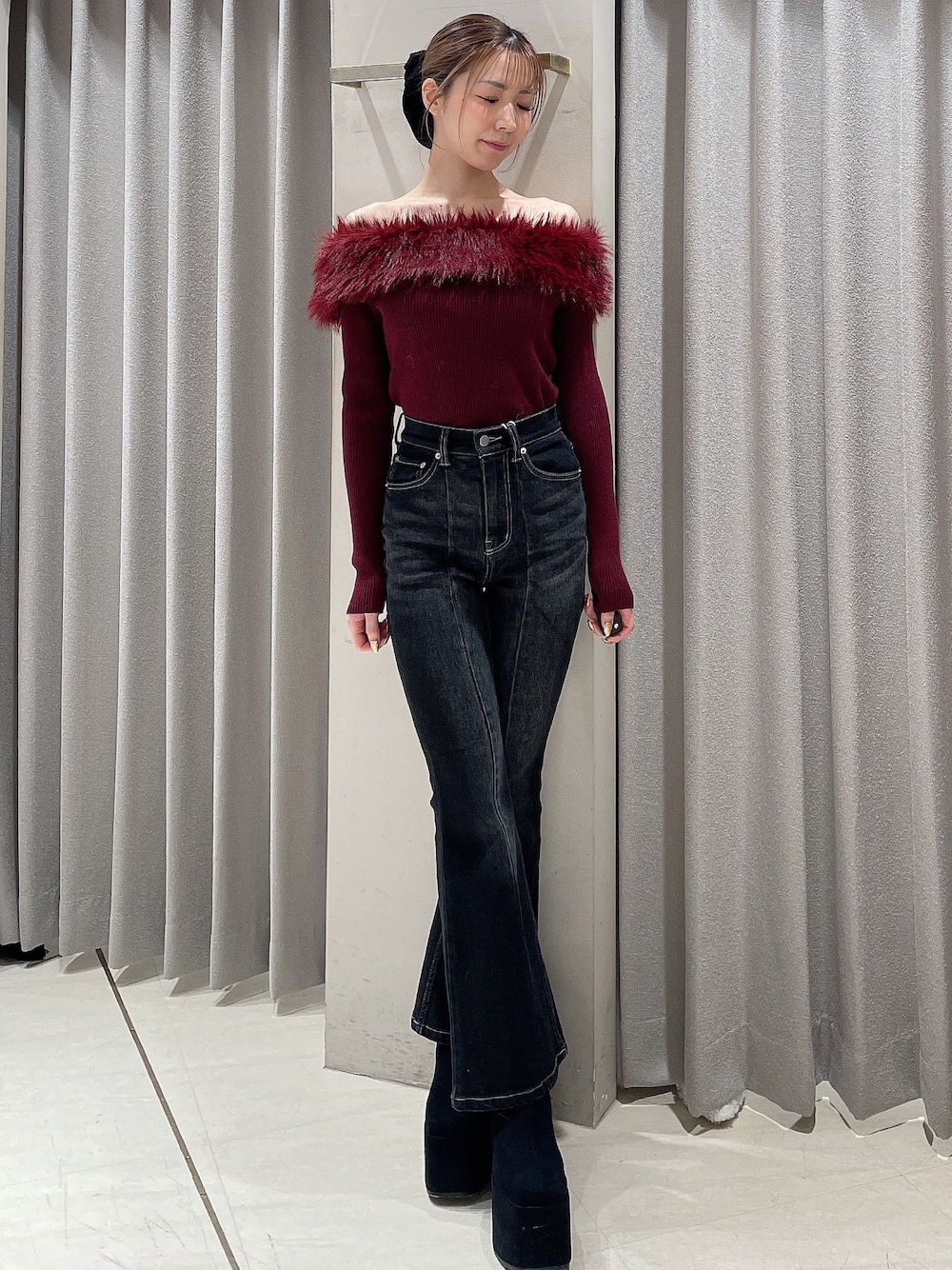 レッド系のニット/セーター、ブラック系のデニムパンツ、ブラック系のブーツを着用したレディースの秋コーディネートの1枚目の写真