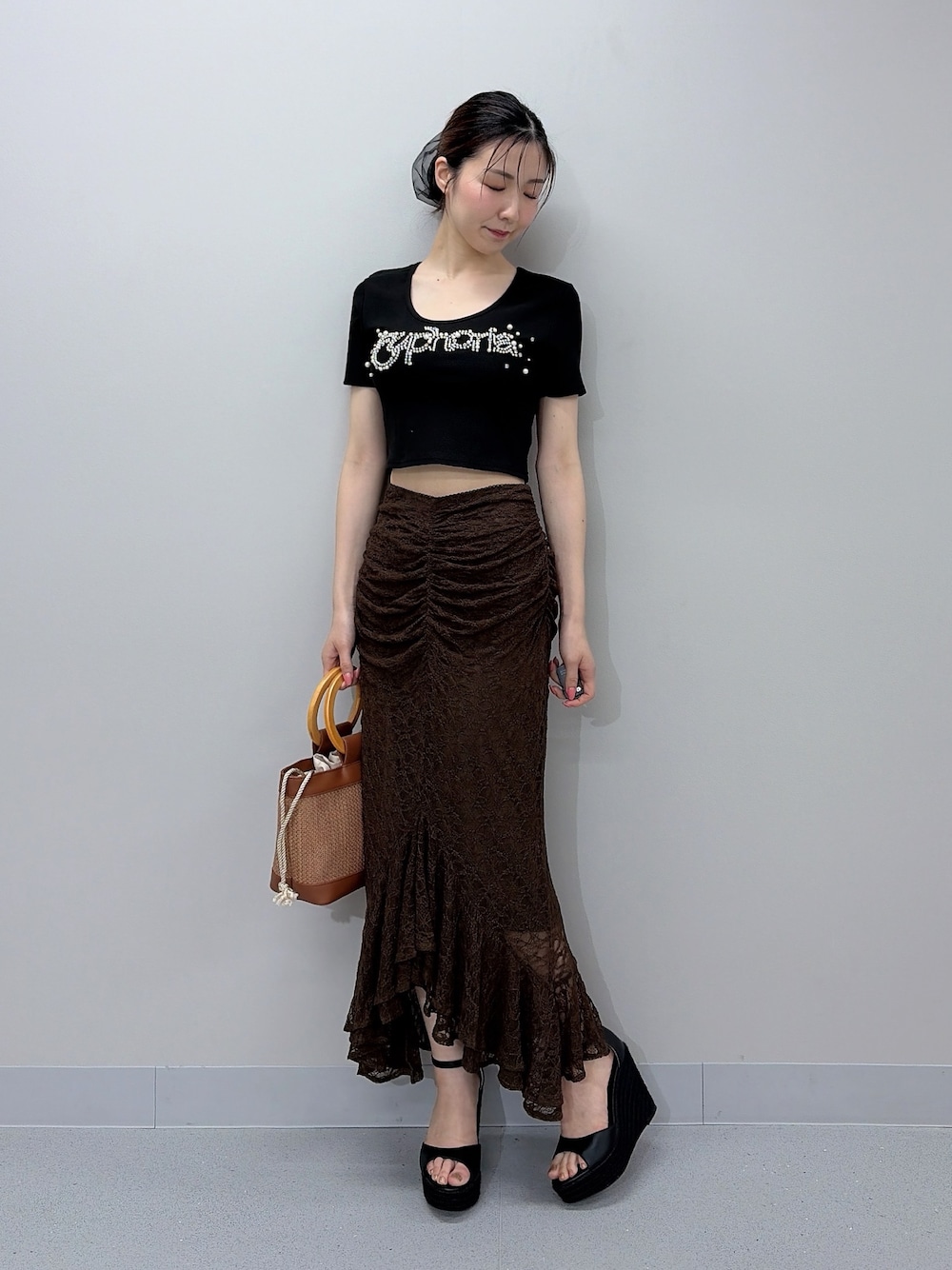 ブラック系のTシャツ/カットソー、ブラウン系のスカート、ブラウン系のハンドバッグを着用したレディースの夏コーディネートの1枚目の写真