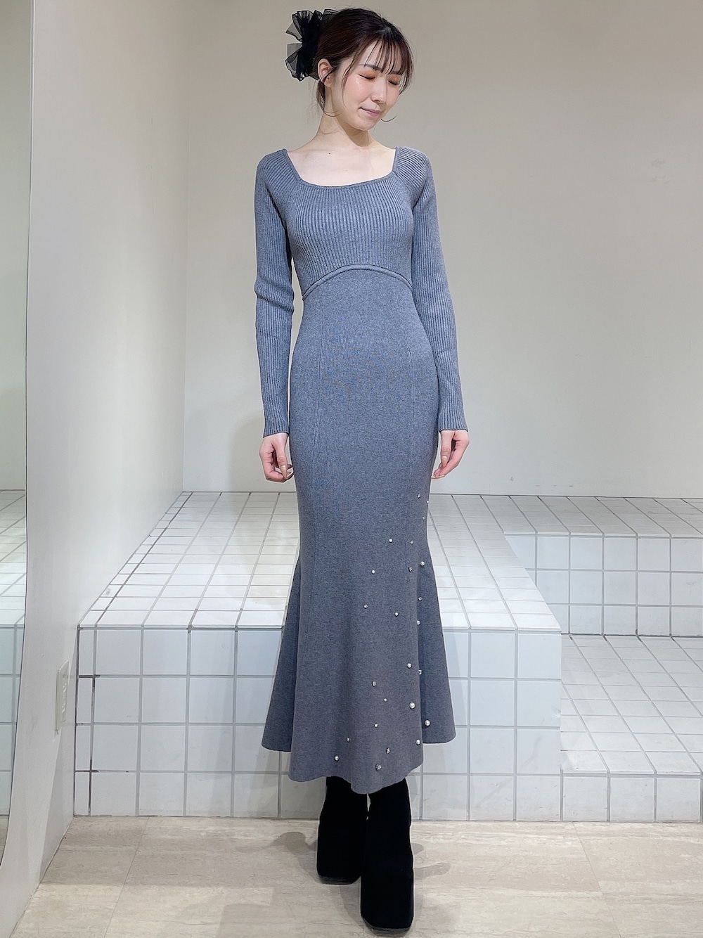 グレー系のワンピース、ブラック系のブーツ、ブラック系のバレッタ/ヘアクリップを着用したレディースの冬コーディネートの1枚目の写真