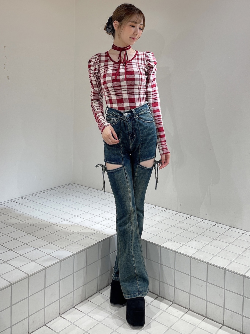 レッド系のニット/セーター、ブルー系のデニムパンツ、ブラック系のブーツを着用したレディースの秋コーディネートの1枚目の写真