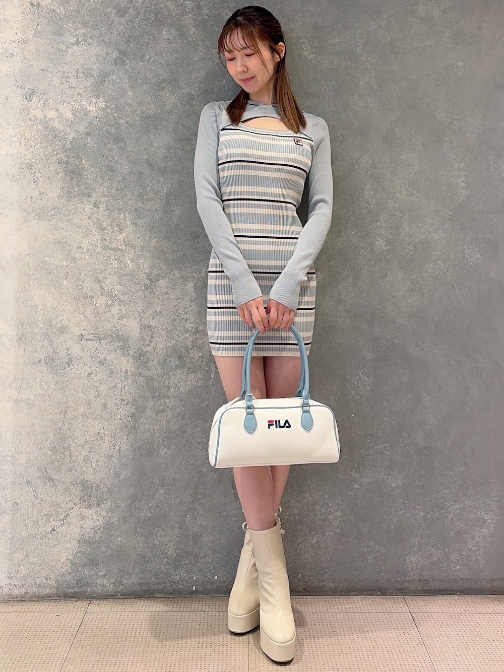 ホワイト系のブーツ、ブルー系のボストンバッグ、ブルー系のワンピースを着用したレディースの冬コーディネートの1枚目の写真