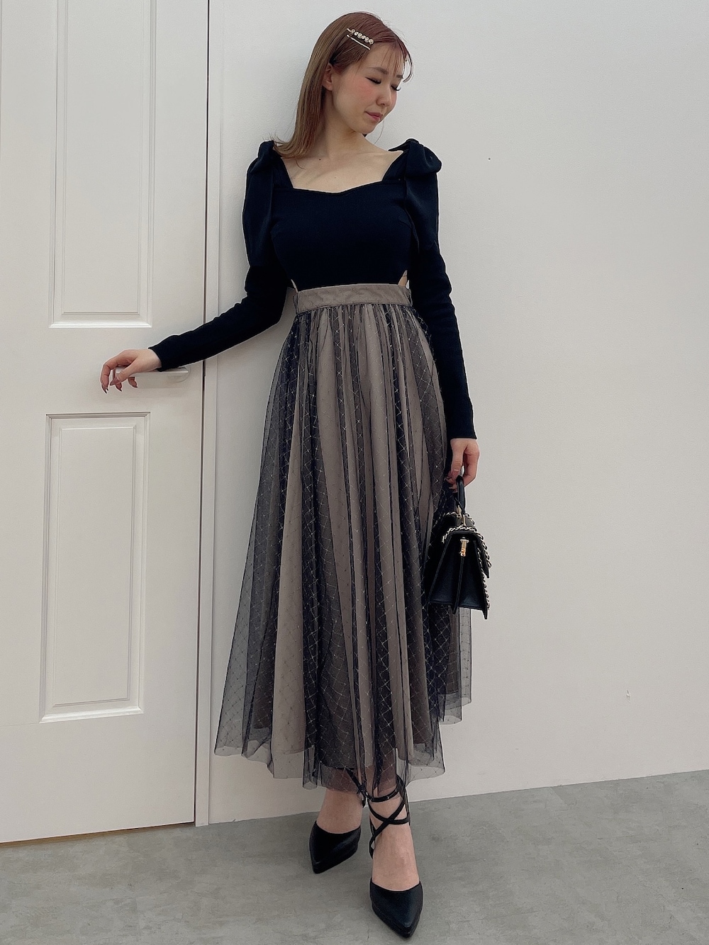 ブラック系のワンピース、ブラック系のハンドバッグ、ブラック系のパンプスを着用したレディースの冬コーディネートの1枚目の写真