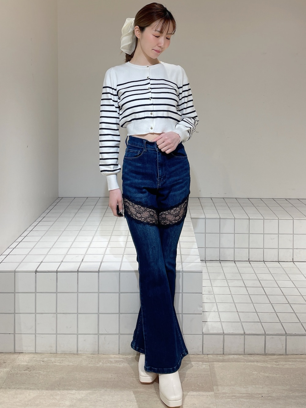 ホワイト系のカーディガン/ボレロ、ブルー系のデニムパンツ、ホワイト系のブーツを着用したレディースの春コーディネートの1枚目の写真