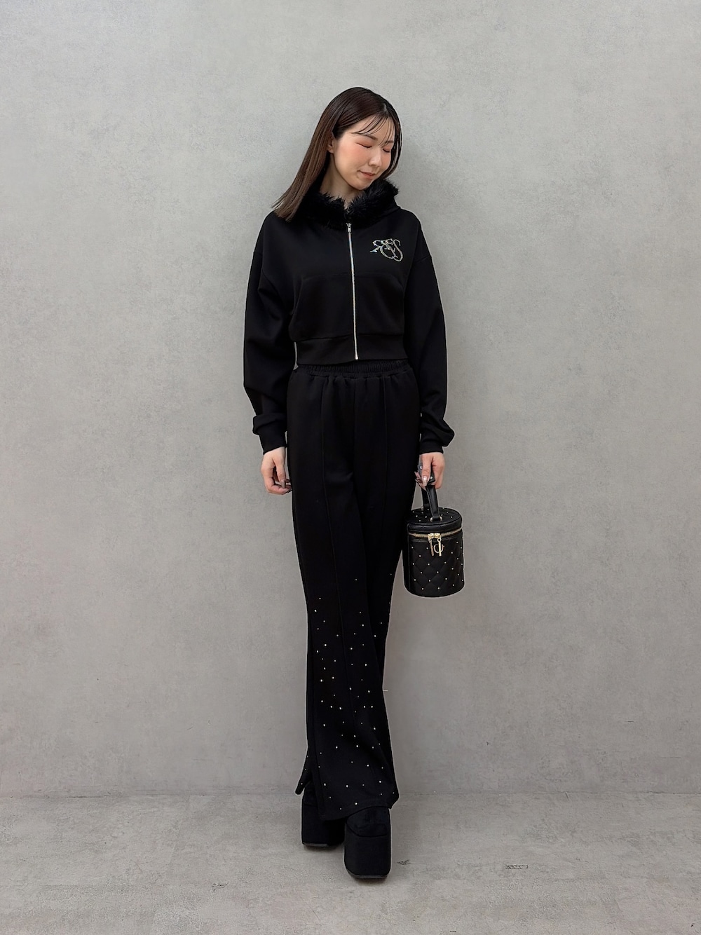 ブラック系のパーカー、ブラック系のスウェットパンツ、ブラック系のハンドバッグを着用したレディースの秋コーディネートの1枚目の写真