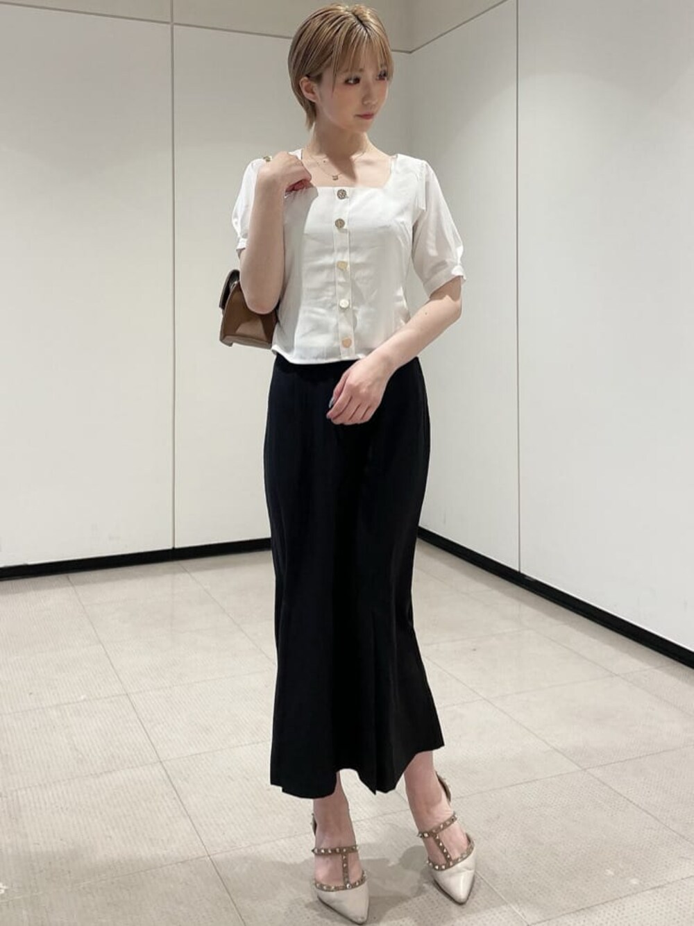 ホワイト系のパンプス、ブラウン系のショルダーバッグ、ホワイト系のシャツ/ブラウスを着用したレディースの夏コーディネートの1枚目の写真