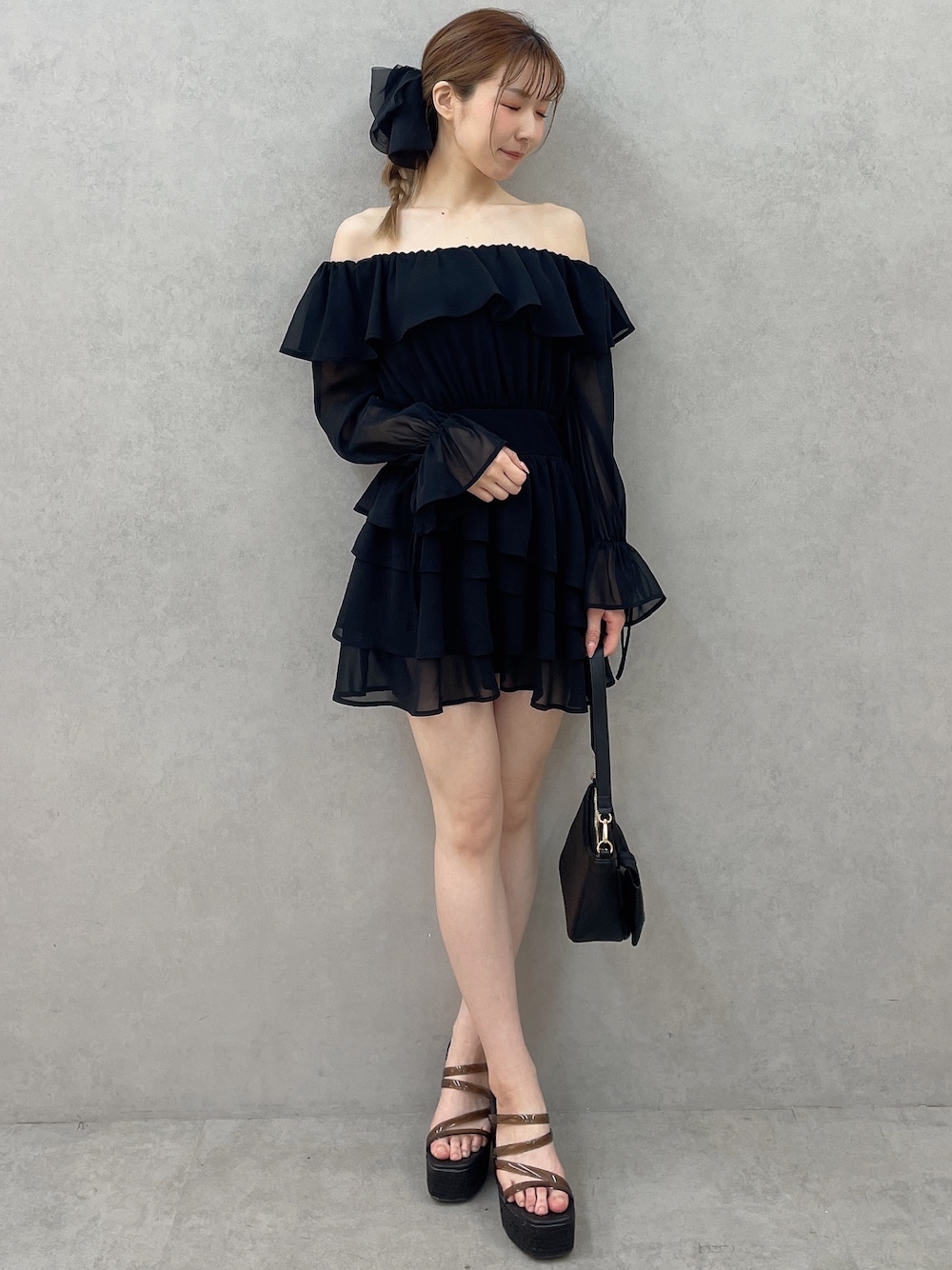 ブラック系のワンピース、ブラック系のハンドバッグ、ブラック系のサンダルを着用したレディースの春コーディネートの1枚目の写真