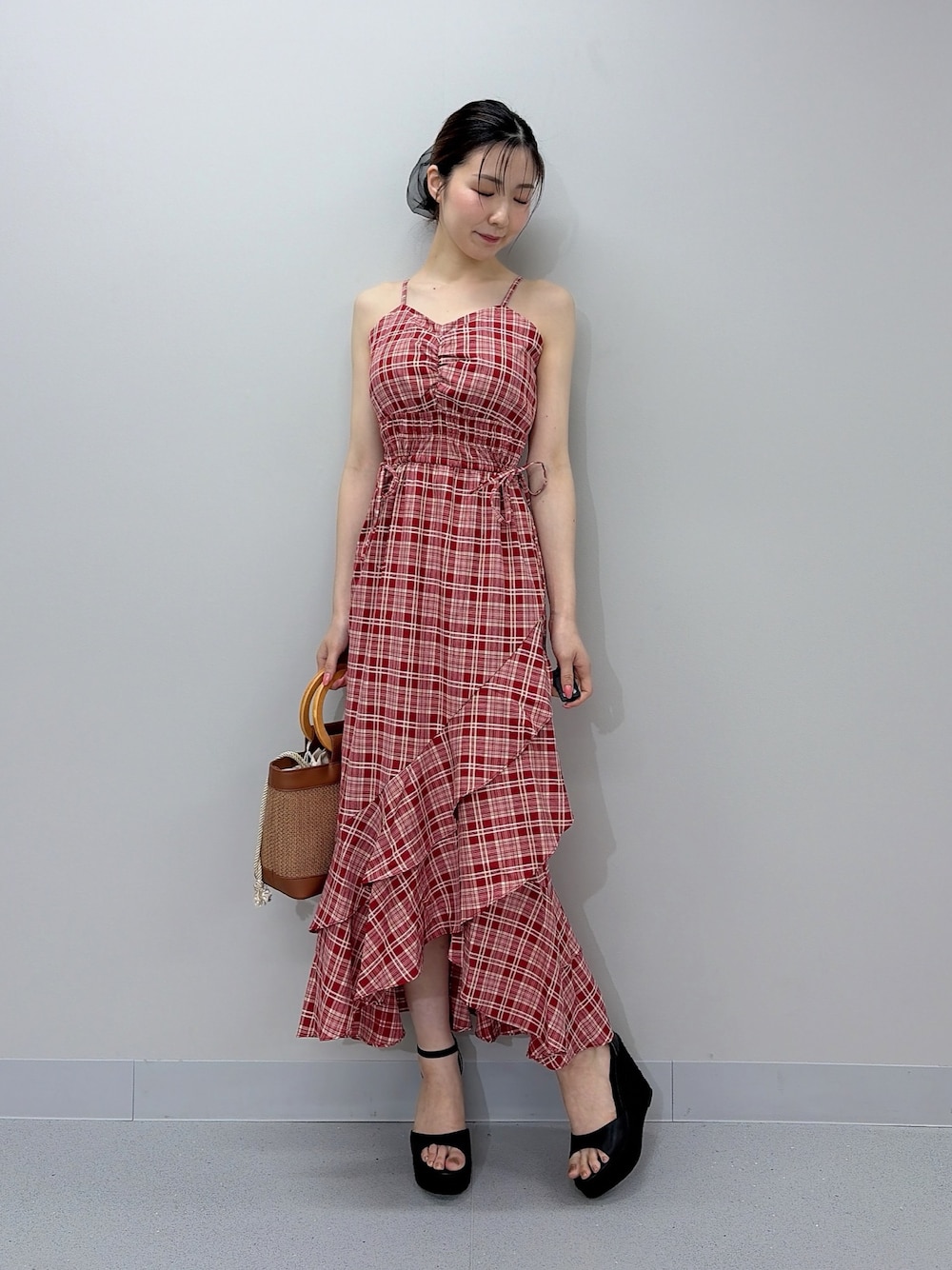 レッド系のワンピース、ブラウン系のハンドバッグ、ブラック系のサンダルを着用したレディースの夏コーディネートの1枚目の写真