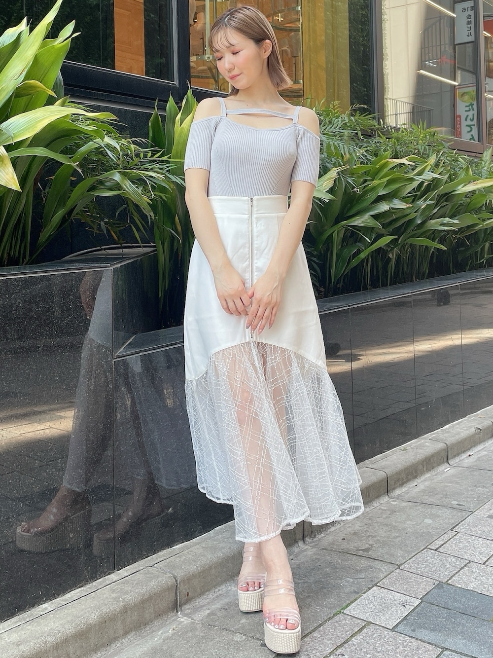 グレー系のニット/セーター、ホワイト系のスカート、ホワイト系のサンダルを着用したレディースの夏コーディネートの1枚目の写真