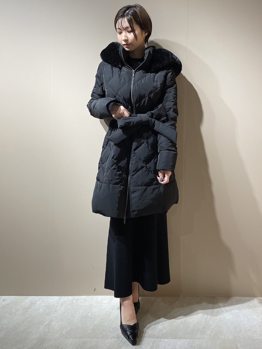 ブラック系のダウンジャケット/コート、ブラック系のワンピース、ブラック系のパンプスを着用したレディースの秋コーディネートの1枚目の写真