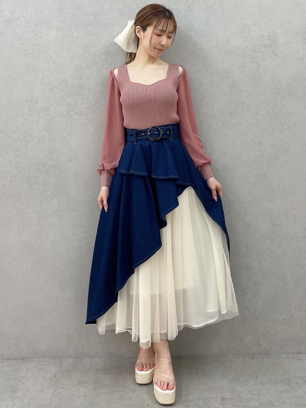 ピンク系のニット/セーター、ブルー系のスカート、ホワイト系のサンダルを着用したレディースの春コーディネートの1枚目の写真