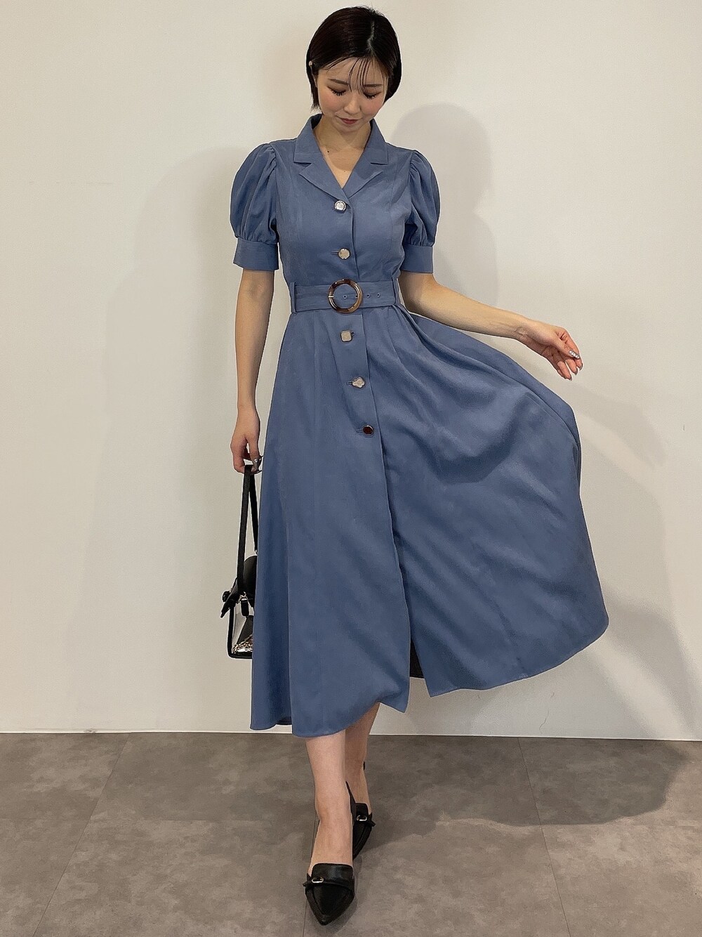 ブルー系のワンピース、ブラック系のパンプス、ブラック系のハンドバッグを着用したレディースの冬コーディネートの1枚目の写真