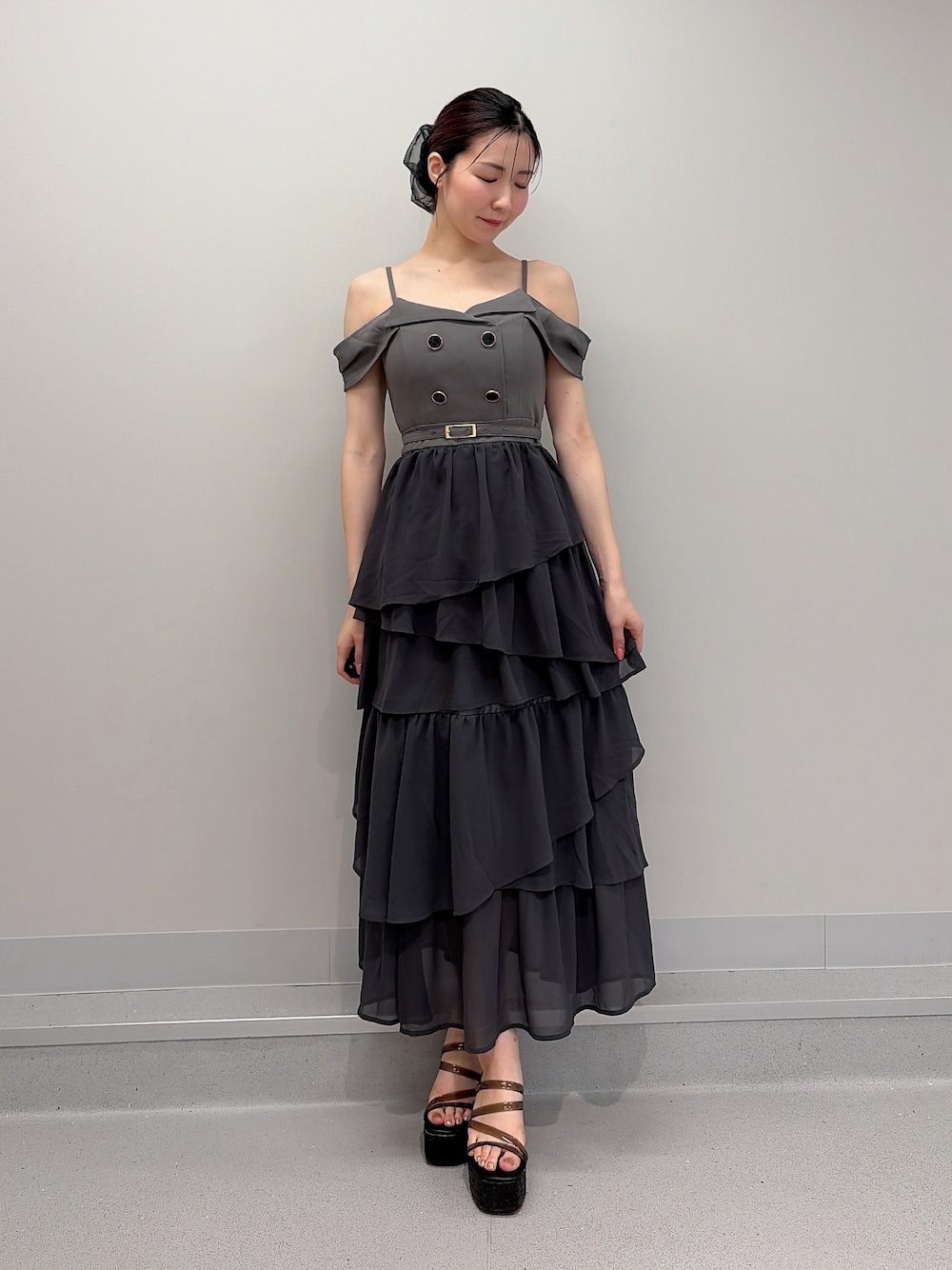 グレー系のワンピース、ブラック系のサンダル、ブラック系のシュシュを着用したレディースの夏コーディネートの1枚目の写真